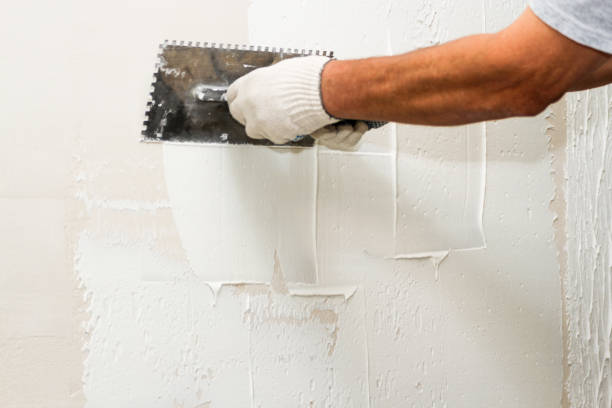 Worker applying joint compound to damaged drywall for a smooth, paint-ready finish by a house painter in Kernersville, NC